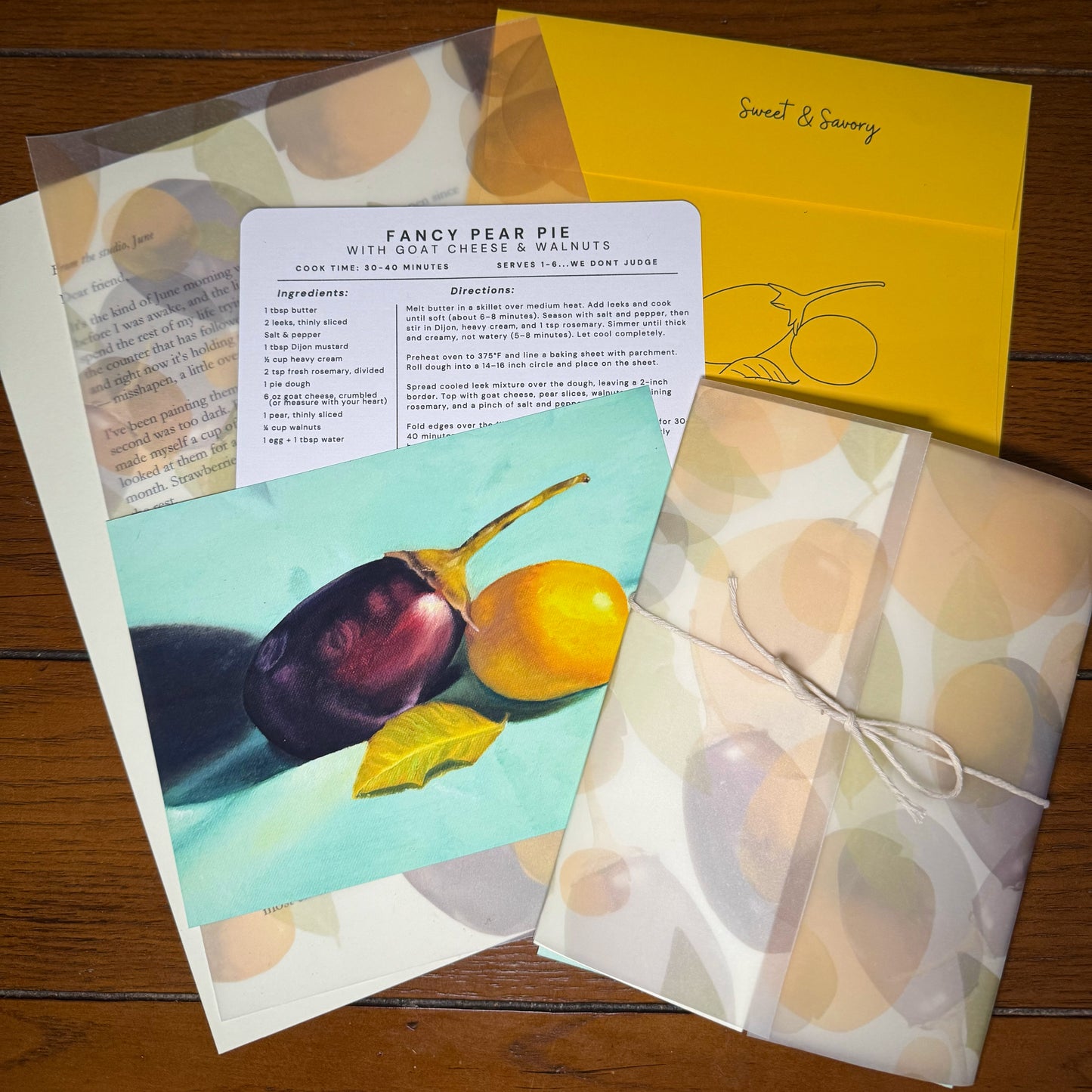 Flat lay of the Sweet & Savory Print Club monthly envelope — a handwritten letter on cream paper, a 5 by 7 original oil painting print, and a recipe card with original art