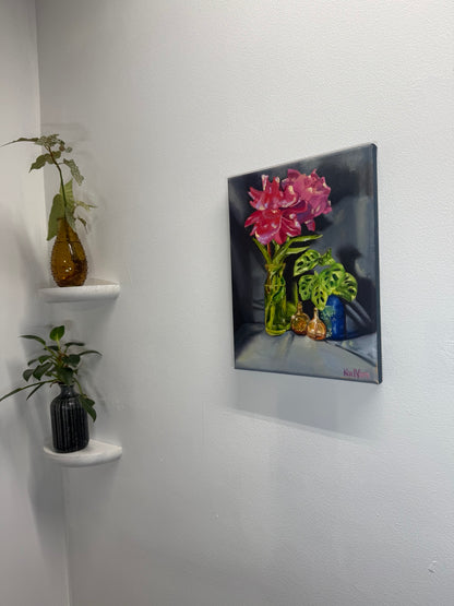 Original floral oil painting displayed on a wall beside two small plant shelves for scale